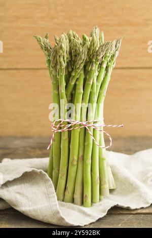 Mazzo di asparagi verdi su tavola di legno con panno di lino Foto Stock