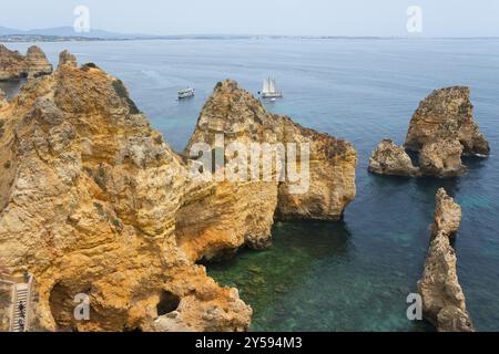 Scogliere e rocce aspre si innalzano dalle acque cristalline vicino a barche a vela, Ponta da Piedade, Point of Mercy, Lagos, Algarve, Portogallo, Europa Foto Stock