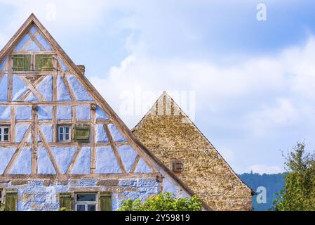 Dettagli architettonici provenienti da due case medievali tedesche, una con pareti in legno blu, piccole finestre, persiane in legno e una con pareti in pietra invecchiata Foto Stock