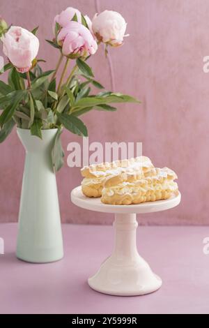 Eclari con ripieno di crema di burro su un supporto per torte Foto Stock