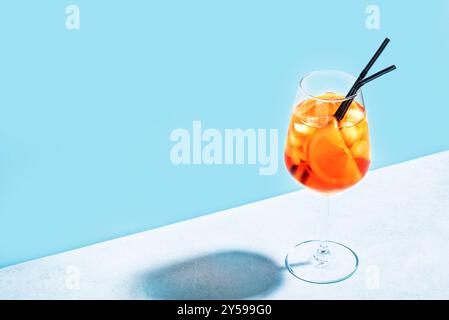 Cocktail Aperol Spritz in vetro con fette arancioni su sfondo azzurro, spazio copia, luce dura alla moda. Deliziosa bevanda estiva Aperol Spritz Aper Foto Stock