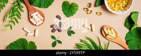 Vitamine naturali, integratori vegetali e foglie verdi su sfondo beige, striscione. Varie capsule e pillole organiche vegane. Foto Stock