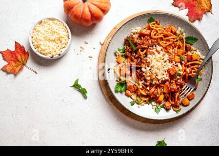 Spaghetti bolognesi di zucca e manzo con parmigiano grattugiato. Spaghetti fatti in casa, zucca e pasta di carne su sfondo bianco in cemento, copia Foto Stock