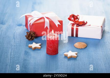 Decorazioni di Natale con piccole scatole regalo, gingerbread cookie e un rosso acceso candela Foto Stock