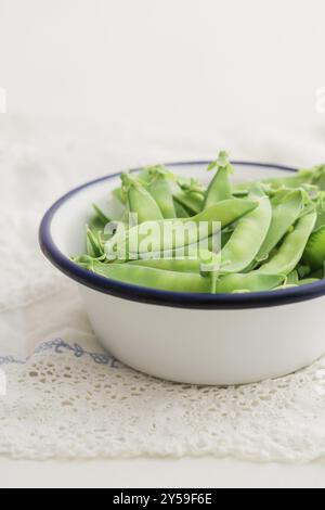 Lo zucchero scatta in una ciotola di smalto bianco su un tavolo con tovaglia di pizzo d'annata Foto Stock