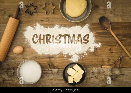 Raccolta di ingredienti e utensili per cuocere i biscotti di Natale con la parola Natale scritta al centro dell'immagine su una W scura Foto Stock