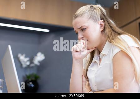 Lavora su un notebook, donna che sembra preoccupata e pensa in ufficio Foto Stock