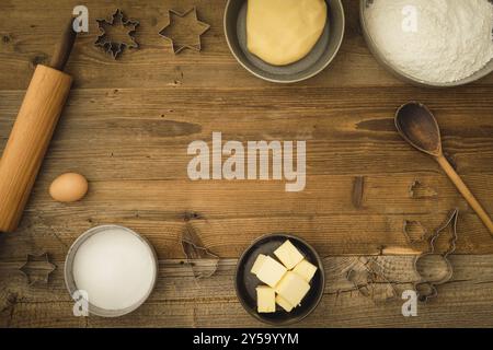 Collezione di ingredienti e utensili per cuocere i biscotti natalizi con spazio di testo al centro dell'immagine su uno sfondo di legno scuro Foto Stock