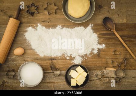 Collezione di ingredienti e utensili per cuocere i biscotti di Natale con farina come spazio di testo al centro dell'immagine su uno sfondo di legno scuro Foto Stock