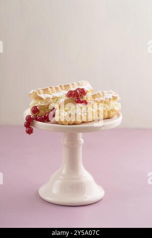 Eclari con ripieno di crema di burro su un supporto per torte Foto Stock