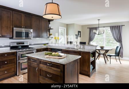 Nuova cucina con armadi in legno scuro e graziosa zona pranzo Foto Stock