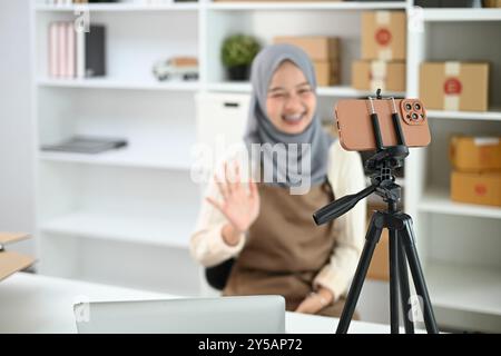 Giovane donna musulmana con hijab che lavora in diretta streaming per vendere prodotti. E-commerce e concetto di piccole imprese Foto Stock