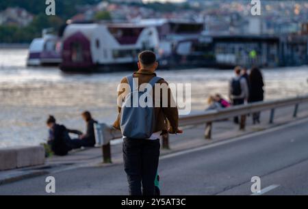 Budapest, Ungheria - 17 settembre 2024: Un uomo in sella a uno scooter elettrico a Budapest con sullo sfondo il fiume Danubio inondato, mettendo in risalto il Foto Stock