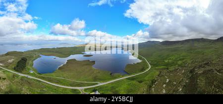 Il percorso panoramico North Coast 500 si snoda intorno a un lago nelle Highlands scozzesi vicino a Old Man of Storr nell'Isola di Skye, Scozia Foto Stock