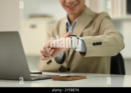 Primo piano uomo d'affari con abbigliamento formale che controlla il tempo su uno smartwatch. Concetto di gestione del tempo Foto Stock