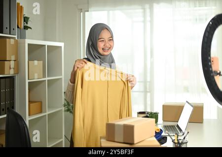 Giovane donna musulmana con hijab che lavora in diretta streaming per vendere prodotti. E-commerce e concetto di piccole imprese Foto Stock