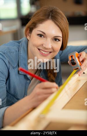 una donna che misura la tavola di legno Foto Stock