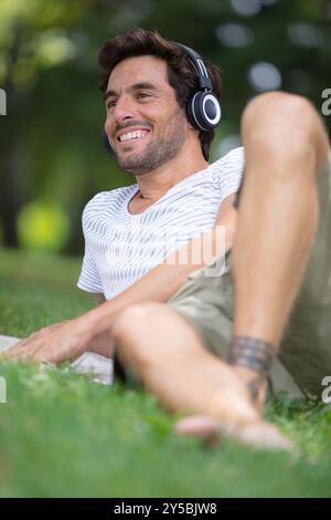 uomo sereno che riposa nel parco e ascolta la musica Foto Stock