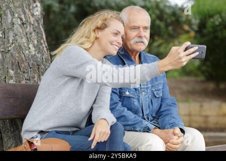 padre in pensione e figlia di mezza età che prende selfie Foto Stock