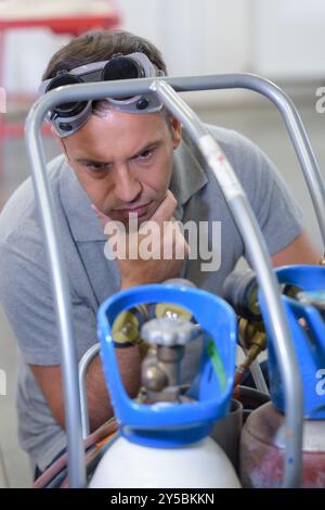 uomo che guarda la bombola di ossigeno Foto Stock