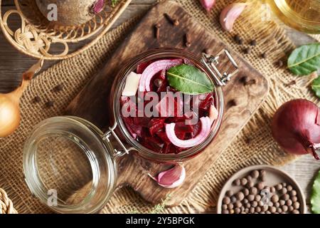 Preparazione di barbabietole fermentate in un vaso di vetro a base di barbabietole fresche, cipolle, aglio e spezie, vista dall'alto Foto Stock