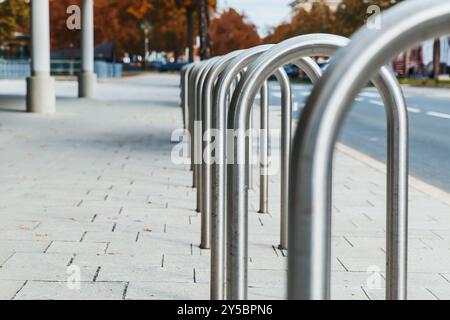 Fila moderna di portabiciclette in metallo sulla strada urbana, un'area parcheggio per biciclette, spazio esterno vuoto in città, concetto di servizi di trasporto Foto Stock