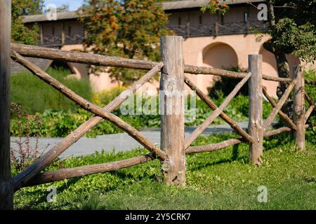 Vecchia barriera in legno per recinzioni presso i terreni dell'azienda agricola per recinzioni di bestiame e territorio. Primo piano frammento di una recinzione in legno vecchio stile. Foto Stock