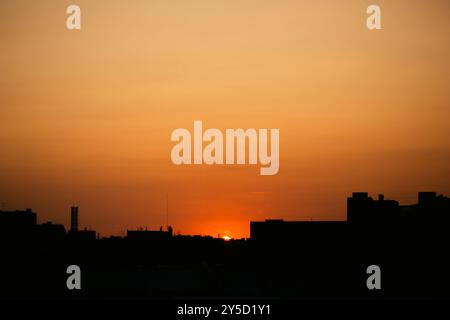 Il sole nascente proietta una splendida luce sulla città, trasformando il cielo di una tonalità arancione. Foto Stock