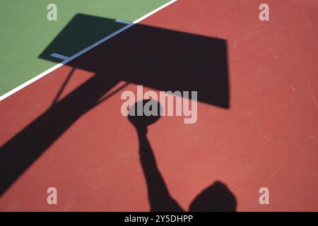 Un'ombra del giocatore di basket lay up su rosso e verde corte Foto Stock