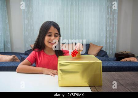 La bambina felice mette il nastro nella confezione regalo Foto Stock