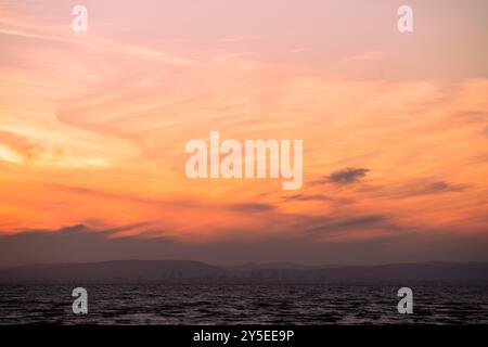 Il sole tramonta sul Galles visto dalla spiaggia di Weston-super-Mare nel Somerset. Foto Stock