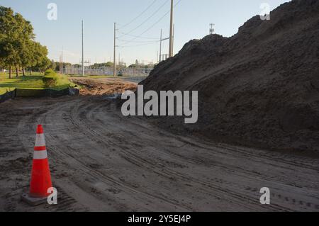 Ampia vista vicino a pali di terra linee principali piste di pneumatici vicino al tramonto grande sottostazione elettrica con linee ad alta potenza in Florida. Silt Fencing, erba verde, Foto Stock