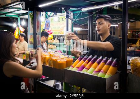 Uomo malese che serve frullati di frutta dai colori vivaci al cibo di strada e al mercato di notte a Kuala lumpur malesia Foto Stock