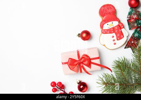 Composizione piatta con decorazioni natalizie, scatola regalo e deliziosi biscotti a forma di pupazzo di neve su sfondo bianco, spazio per il testo Foto Stock