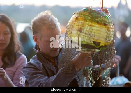 Seattle, Washington, Stati Uniti. 21 settembre 2024. Un volontario dà il tocco finale a una lanterna durante la celebrazione autunnale equinozio della Luminata al Green Lake Park di Seattle. Il Fremont Arts Council accoglie tutti alla processione intorno a Green Lake per celebrare l'equinozio autunnale con costumi illuminati, lanterne e arte. Crediti: Paul Christian Gordon/Alamy Live News Foto Stock