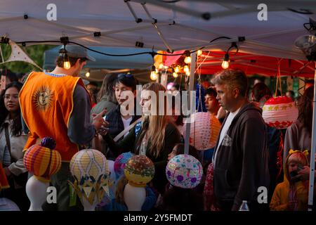 Seattle, Washington, Stati Uniti. 21 settembre 2024. Un volontario aiuta i visitatori con le lanterne alla celebrazione autunnale equinozio della Luminata al Green Lake Park di Seattle. Il Fremont Arts Council accoglie tutti alla processione intorno a Green Lake per celebrare l'equinozio autunnale con costumi illuminati, lanterne e arte. Crediti: Paul Christian Gordon/Alamy Live News Foto Stock