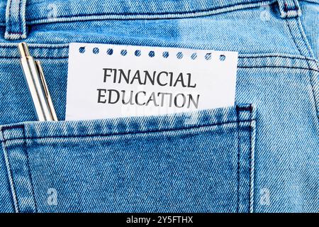 Business Financial Education. Copia spazio. Parole concettuali EDUCAZIONE FINANZIARIA su un pezzo di carta che esce dalla tasca di un jeans Foto Stock