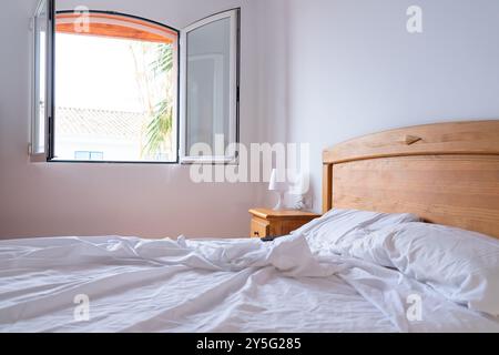 Camera da letto con letto doppio non fatto e luce naturale dalla finestra Foto Stock