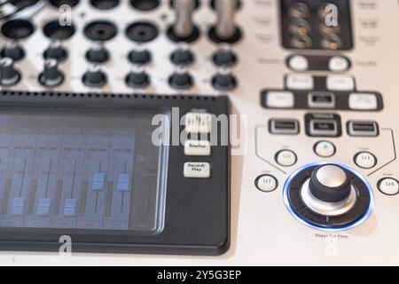 Primo piano di un mixer audio professionale con varie manopole, pulsanti e display digitale. L'immagine mostra gli intricati controlli utilizzati per l'audio Foto Stock