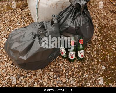 Fodere nere piene e bottiglie vuote sedute sul nucleo duro, rifiuti raccolti dopo una pulizia della corsia nell'Hampshire, Regno Unito Foto Stock