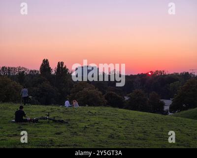 Le persone guardano il tramonto sulla collina Olympia che si affaccia sul Parco Olimpico di Monaco, la Germania guarda il tramonto sulla collina Olympia che si affaccia su di te Foto Stock