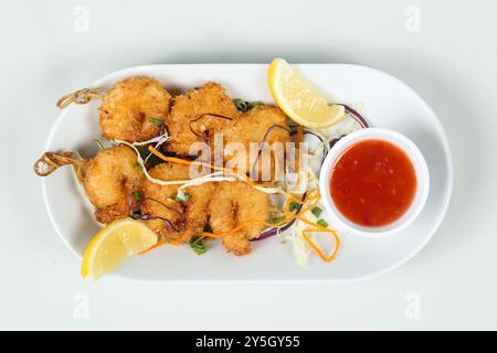 gamberi fritti in profondità su spiedini in un piatto bianco. comodo servizio di spuntini al banchetto. rinfresco per i bambini. vista dall'alto Foto Stock