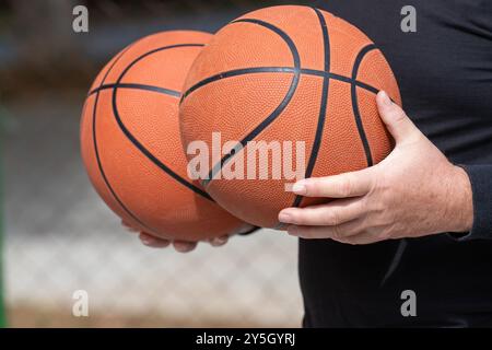 Uomo in abito sportivo nero con due palloni da basket - pronto per l'azione Street Ball. Foto Stock