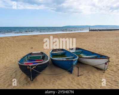Middle Chine Beach, Bournemouth, Regno Unito - 6 giugno 2024: Tre barche a remi incatenate sulla spiaggia sabbiosa. Foto Stock