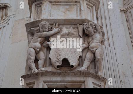 SIBENIK, CROAZIA - 9 SETTEMBRE 2016: Questo è un frammento architettonico con figure di cherubini con un rotolo sulla facciata della cattedrale di San Già Foto Stock