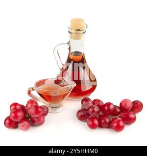 Aceto di vino in bottiglia e uva isolata su fondo bianco. Foto Stock