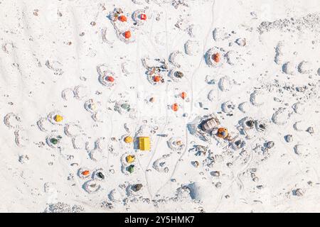 Vista aerea dall'alto verso il basso del rifugio Bethlemi o del campo base della stazione meteo con colorate tende gialle arancioni nella neve. Arrampicata sul monte Kazbek nel parco nazionale di Kazbegi Foto Stock