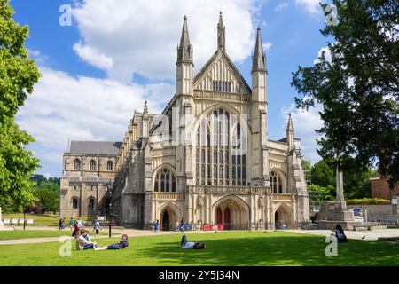 Facciata ovest della cattedrale di Winchester con gente che gode il sole nella cattedrale vicino a Winchester Hampshire Inghilterra Regno Unito Europa Foto Stock