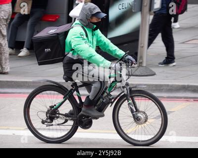 Consegna del cibo Uber mangia rider con maschera sulla bici elettrica, Bishopsgate, Londra Regno Unito Foto Stock