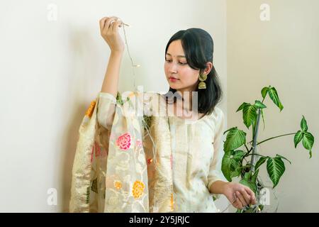 Bella donna asiatica a Kurtha per Diwali che dà espressioni e gesti con luci natalizie a LED Foto Stock